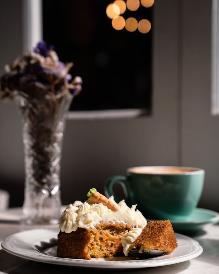 Carrot cake slice with coffee cup in cozy indoor setting.